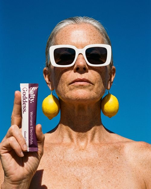 Woman with lemon earrings and red lips holding a Salty Goddess pouch