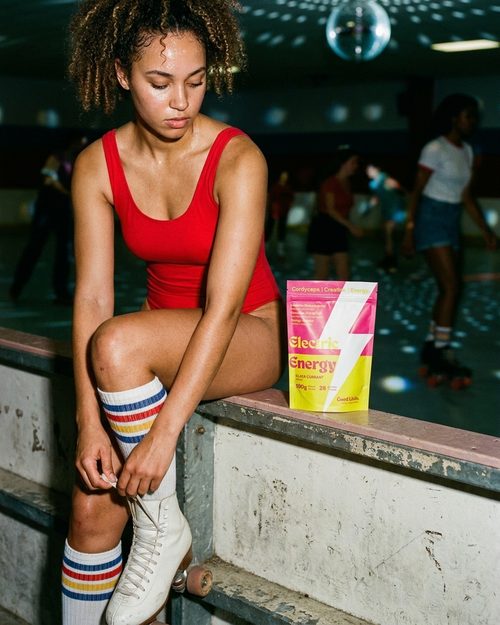 Roller skater in a red leotard at a rink with an Electric Energy pouch